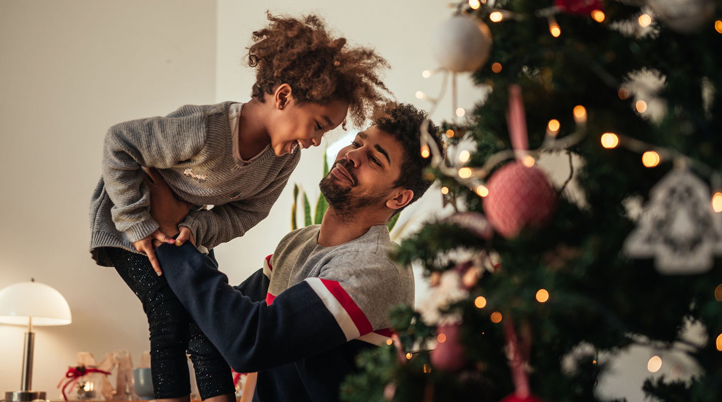 dad and daughter playing next to christmas tree