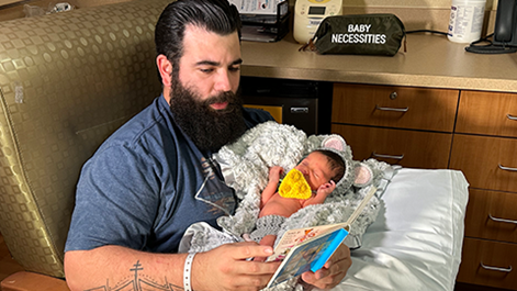 dad reading to newborn at Joe DiMaggio Children's NICU