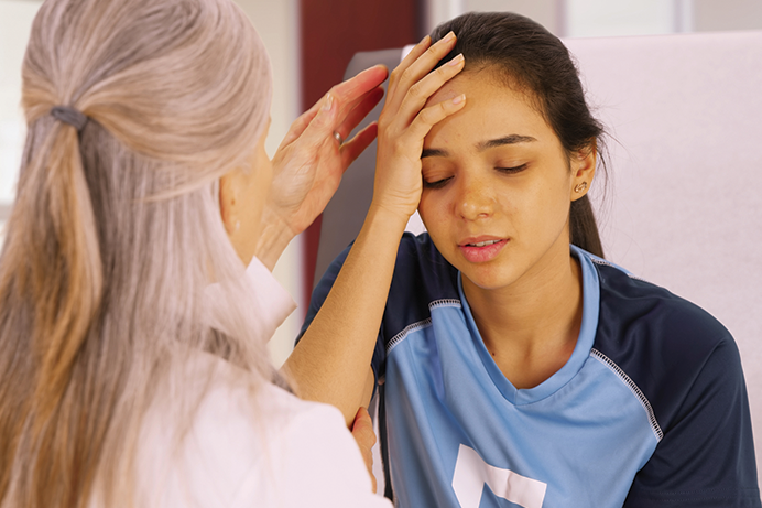 doctor examining head of injured teen girl