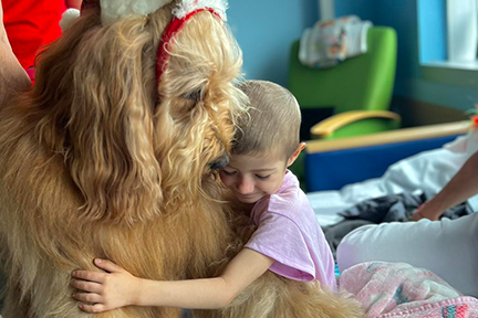 Girl hugging Brodie in hospital bed