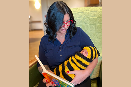 Mom reading to newborn at MHM NICU Read-a-thon 2024