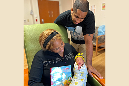 Dad, mom, and newborn at MHM NICU Read-a-thon 2024