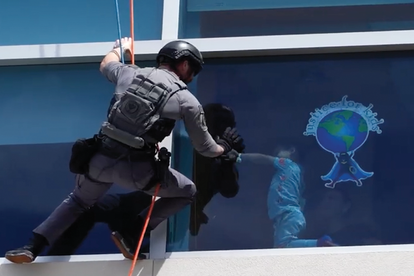 First responder rappelling outside Joe DiMaggio Children's Hospital waving at pediatric patient