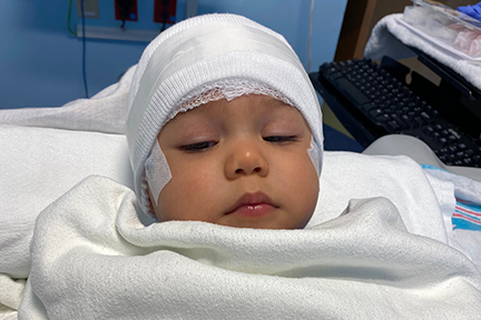 Giovanni wearing bandages on head in hospital bed