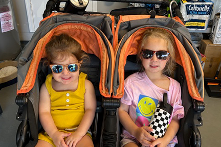 Emilia and Vivian wearing sunglasses in double stroller