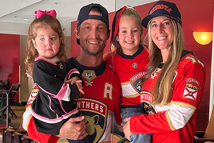 Emilia, Vivian and their parents wearing Florida Panthers jerseys at game
