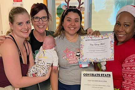 Emily holding Casey celebrating his NICU graduation with his newborn care team