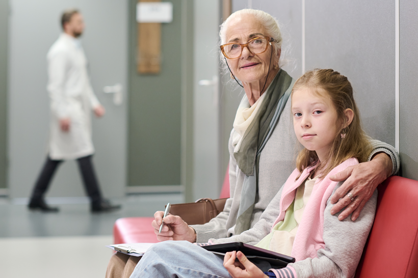 Healthcare Surrogate grandmother with grandchild in waiting room at the doctor's office