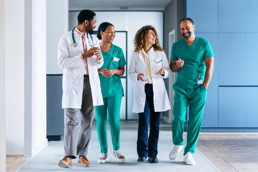 four medical professionals talking in a hospital hall
