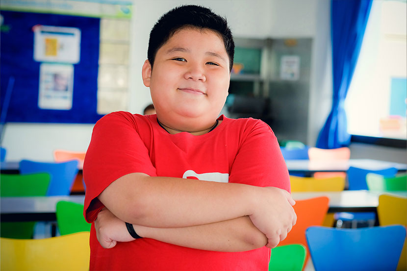 Little boy posing in front of classroom.
