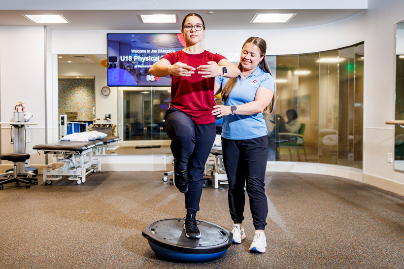 Young female patient with therapist performing balance exercises during a sport therapy session