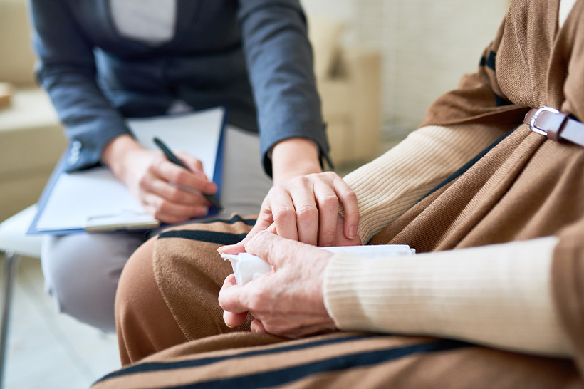 A woman gently holds the hand of an older woman in a moment of connection and support.