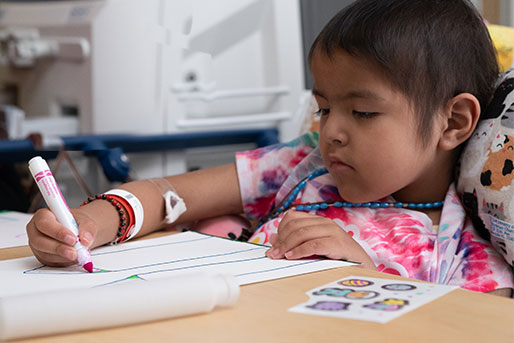 Young Patient coloring at her bedside with a child life specialist